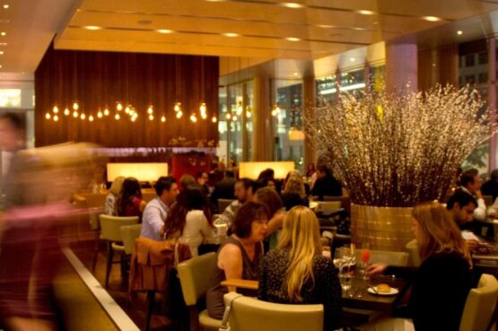 A warm shot of Luma's interior with high ceilings and lounge chairs where people are gathering.