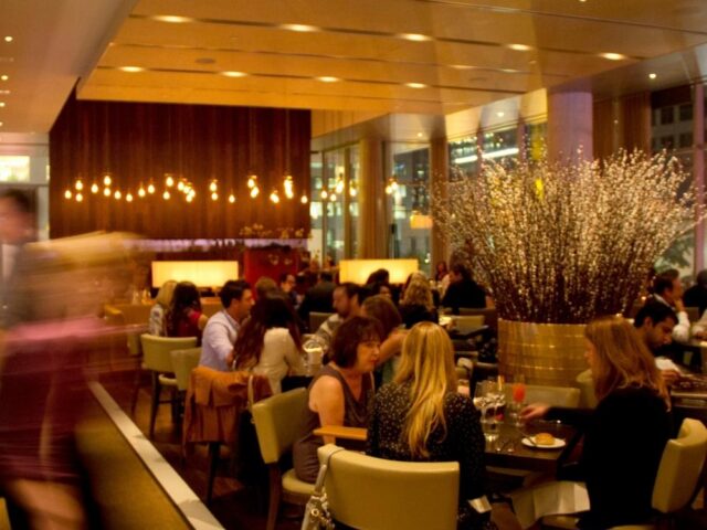 A warm shot of Luma's interior with high ceilings and lounge chairs where people are gathering.