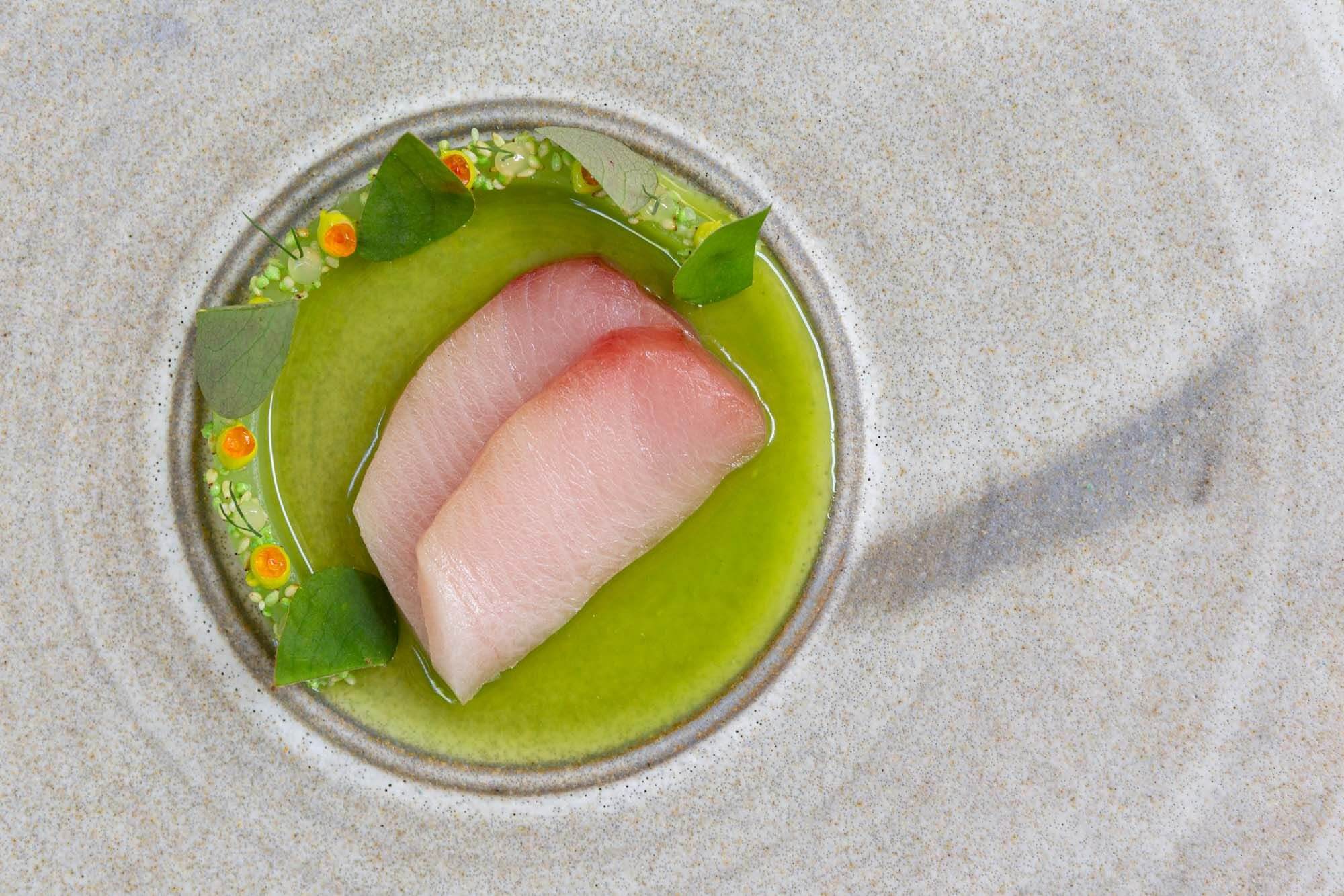 Auberge du Pommier tasting menu dish on round gray plate with green sauce