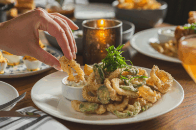 Hand dipping Crispy Calamari in tartar sauce