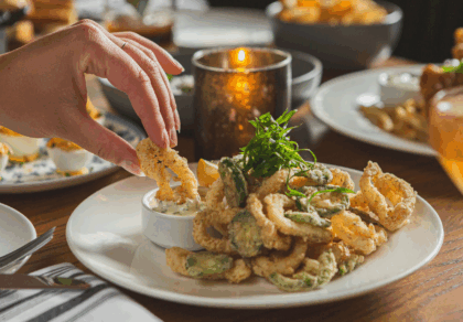 Hand dipping Crispy Calamari in tartar sauce