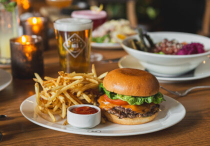 the guild burger sits on white plate with fries and ramekin of ketchup