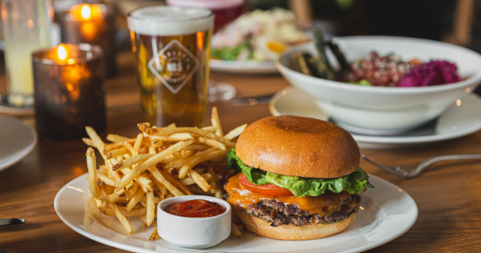 the guild burger sits on white plate with fries and ramekin of ketchup