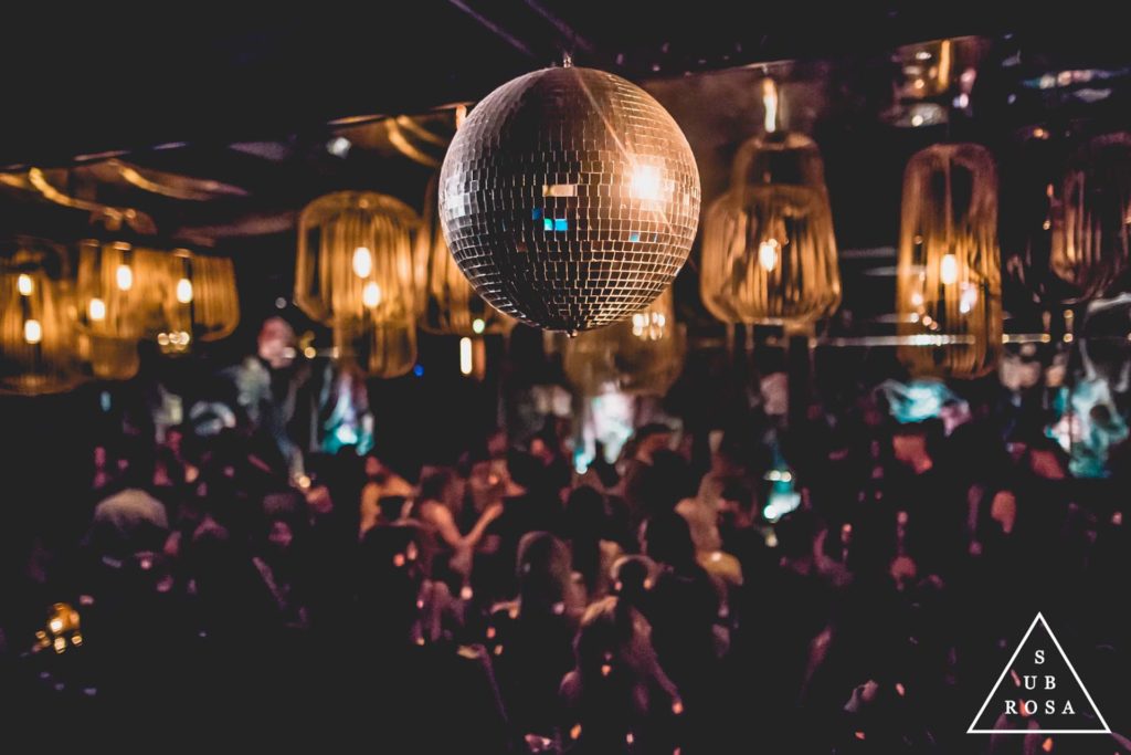 a disco ball hanging over a group of people in an underground lounge