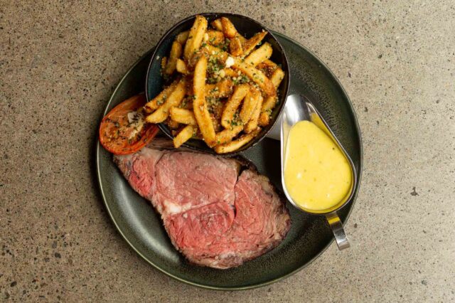 plate of prime rib, truffle Parmesan fries, green beans, roasted tomato, beer-naise sauce