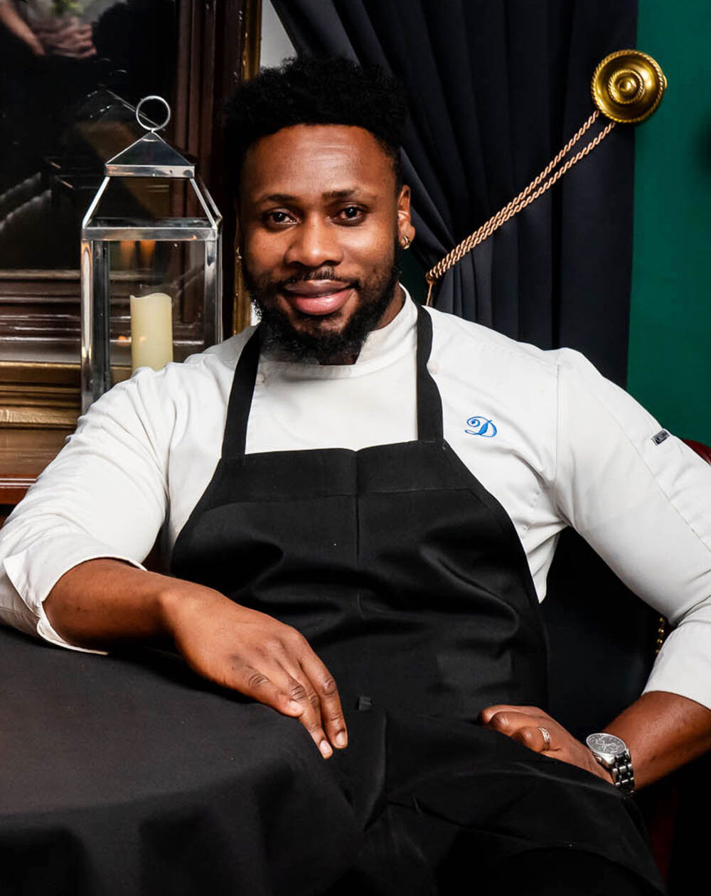 Chef de Cuisine Donnel English in white chef's coat and black apron, seated in elegant restaurant setting