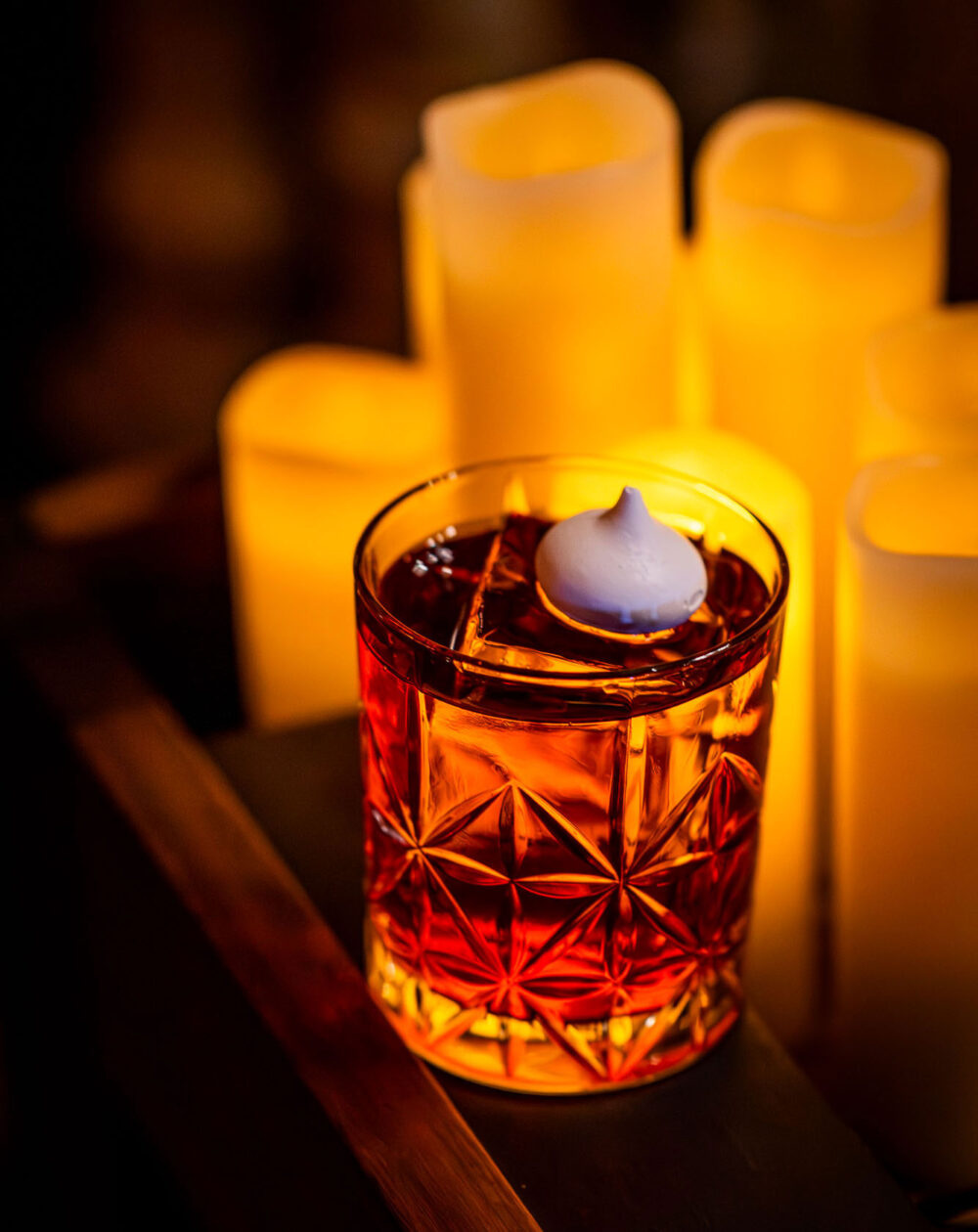 a cocktail in a whisky glass with a merangue garnish