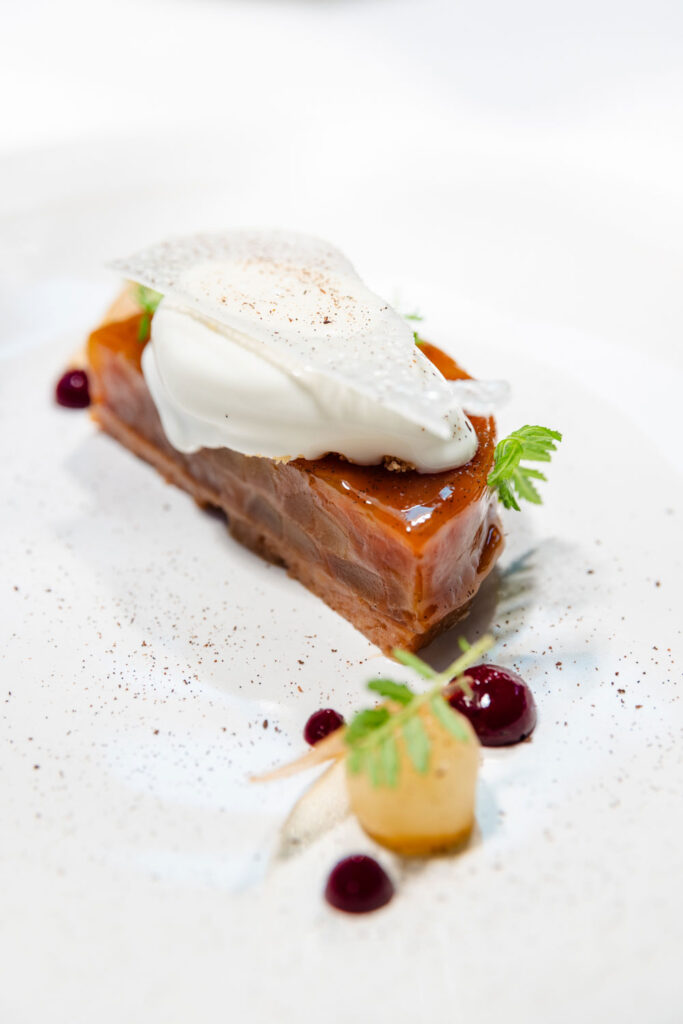 a white plate topped with a piece of cake and whipped cream
