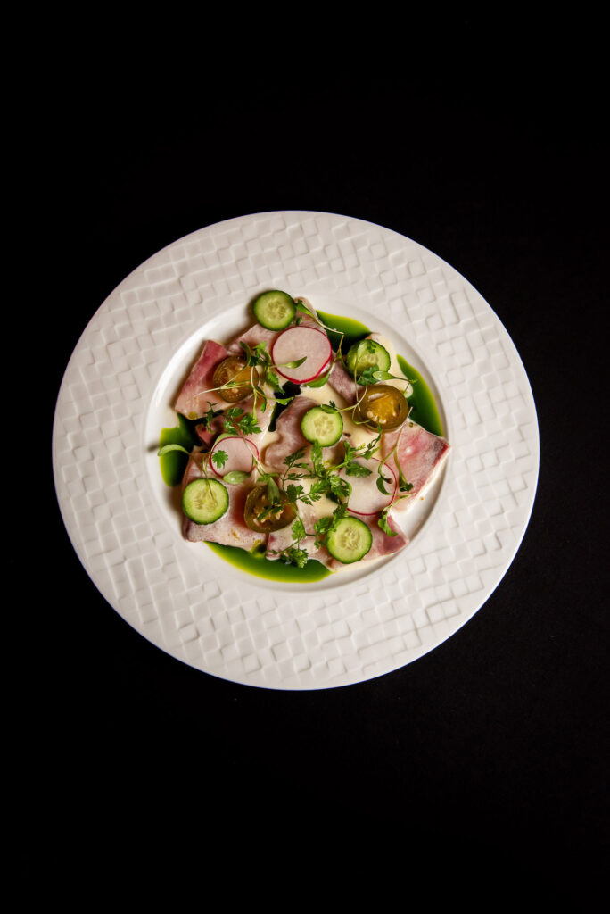 a white plate topped with a salad of cucumbers and ham