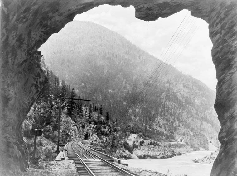 a black and white photo of a train going through a tunnel
