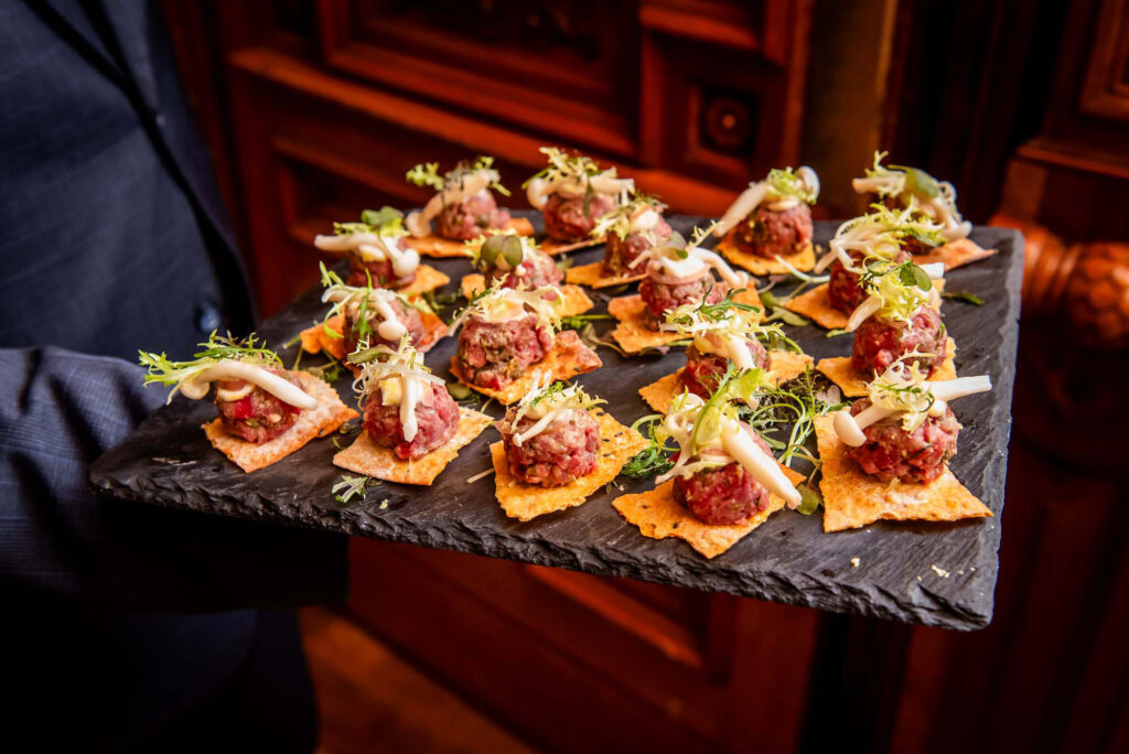 a person holding a tray of appetizers on a table
