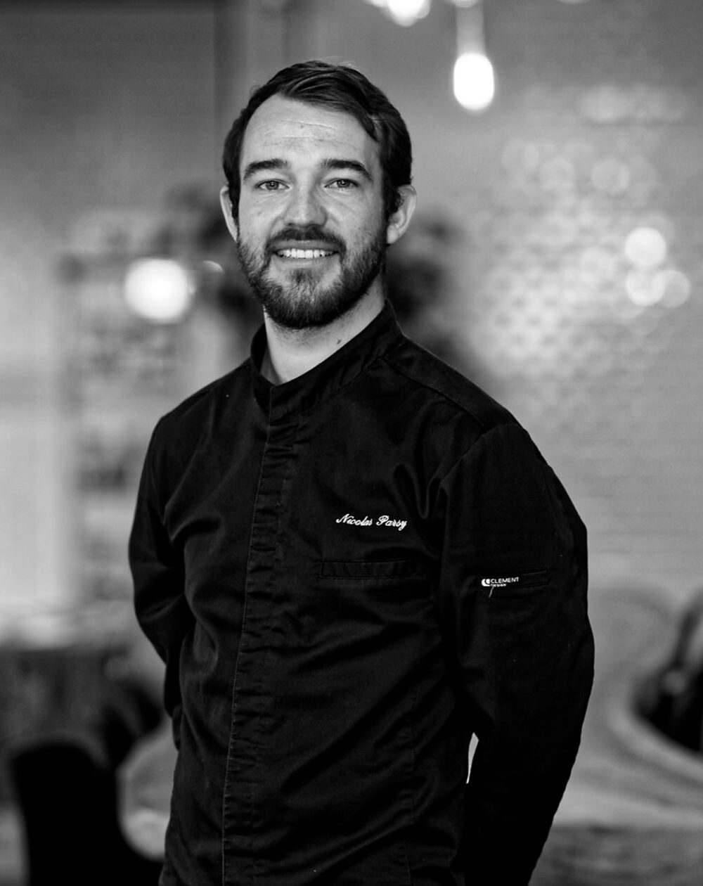 Pastry Chef Nicolas Parsy in black chef's coat, photographed in restaurant setting
