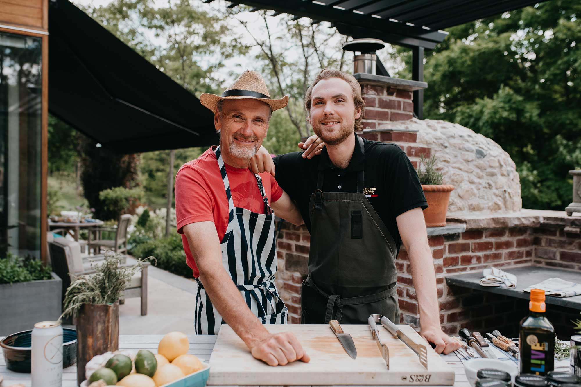 Chef Michael Bonacini and his son Oscar cooking together in an outdoor kitchen