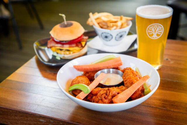 how wings in white dish with beer and burger in the backgorund