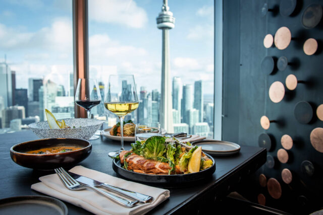 Aera Winterlicious entrees sitting on a dark wood table top with the Toronto skyline in the background