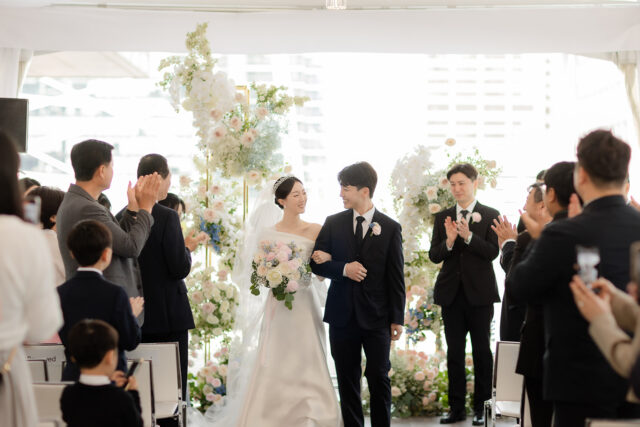 Bride and groom walking up the aisle while guests applaud at their wedding at Malaparte in downtown Toronto