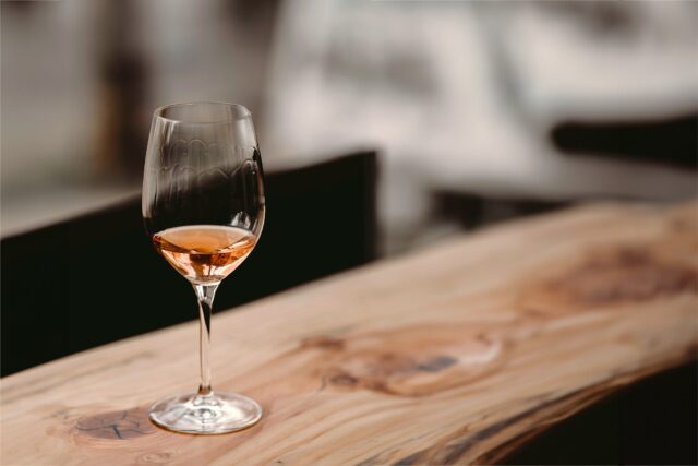 a glass of rose sits ona. wood grain table