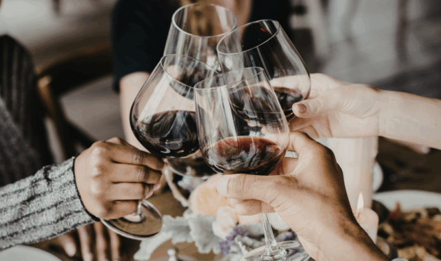 Full happy family clinking glasses over a table indoors.