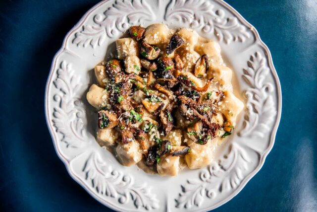 PORCINI & RICOTTA GNOCCHI at parcheggio on white decortive plate and blue background
