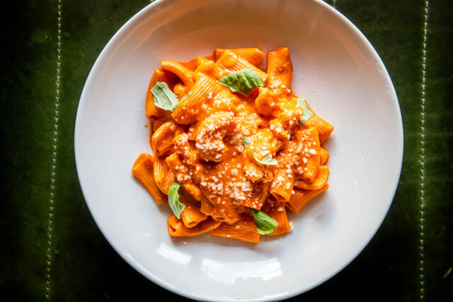 SHRIMP RIGATONI ROSÉ in white dish on green background parcheggio toronto