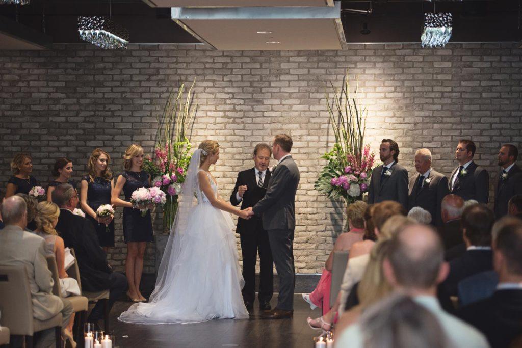 Bride and groom holding hands during ceremony at Arcadian Loft