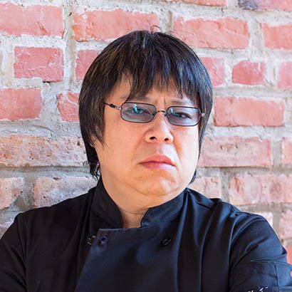 headshot of Chef Alvin Leung standing against a brick wall