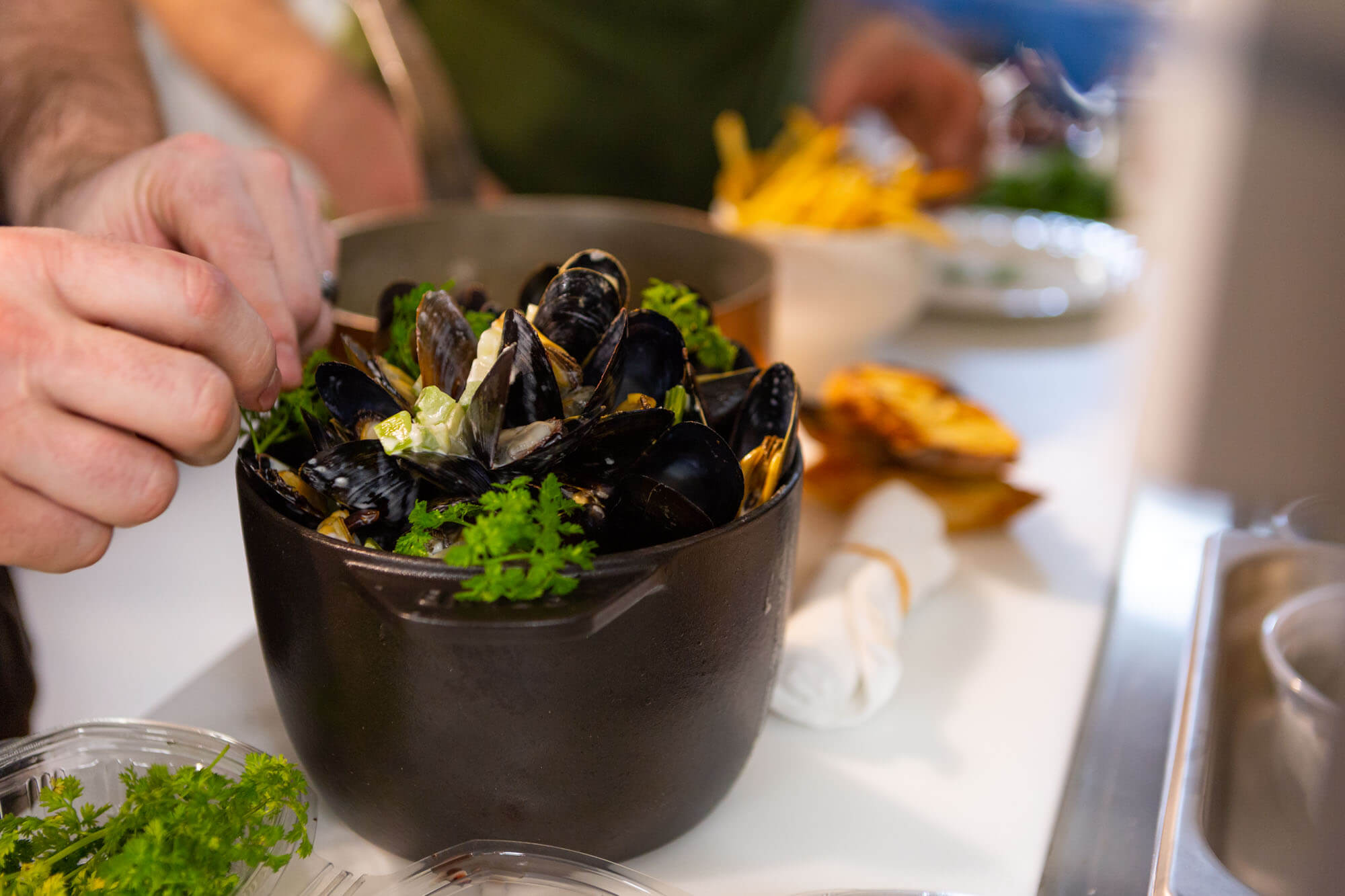 Chef placing garnishes on moules frite in the Maison Selby kitchen