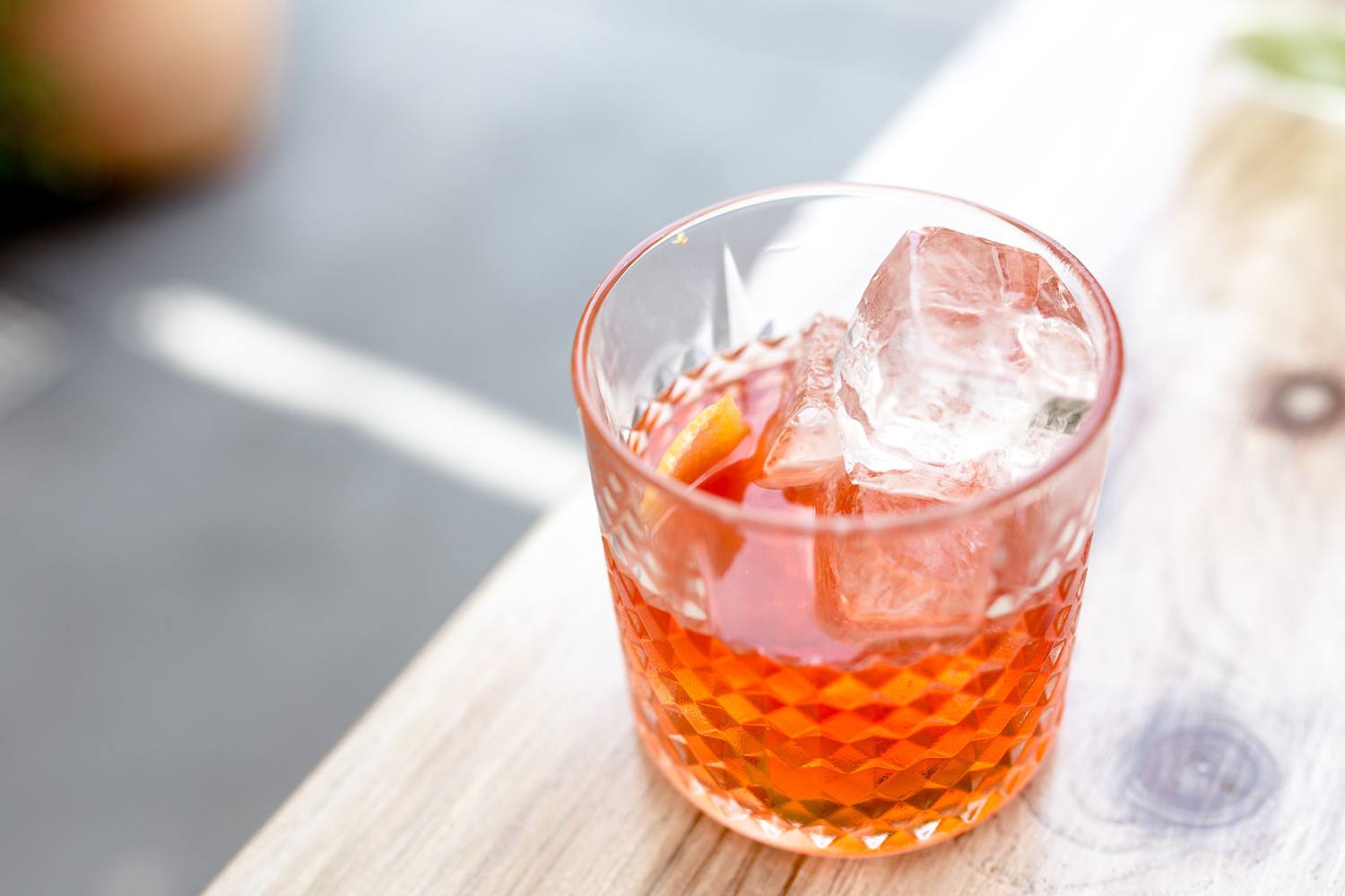 Classic negroni cocktail served in a rocks glass on a wooden table outside.