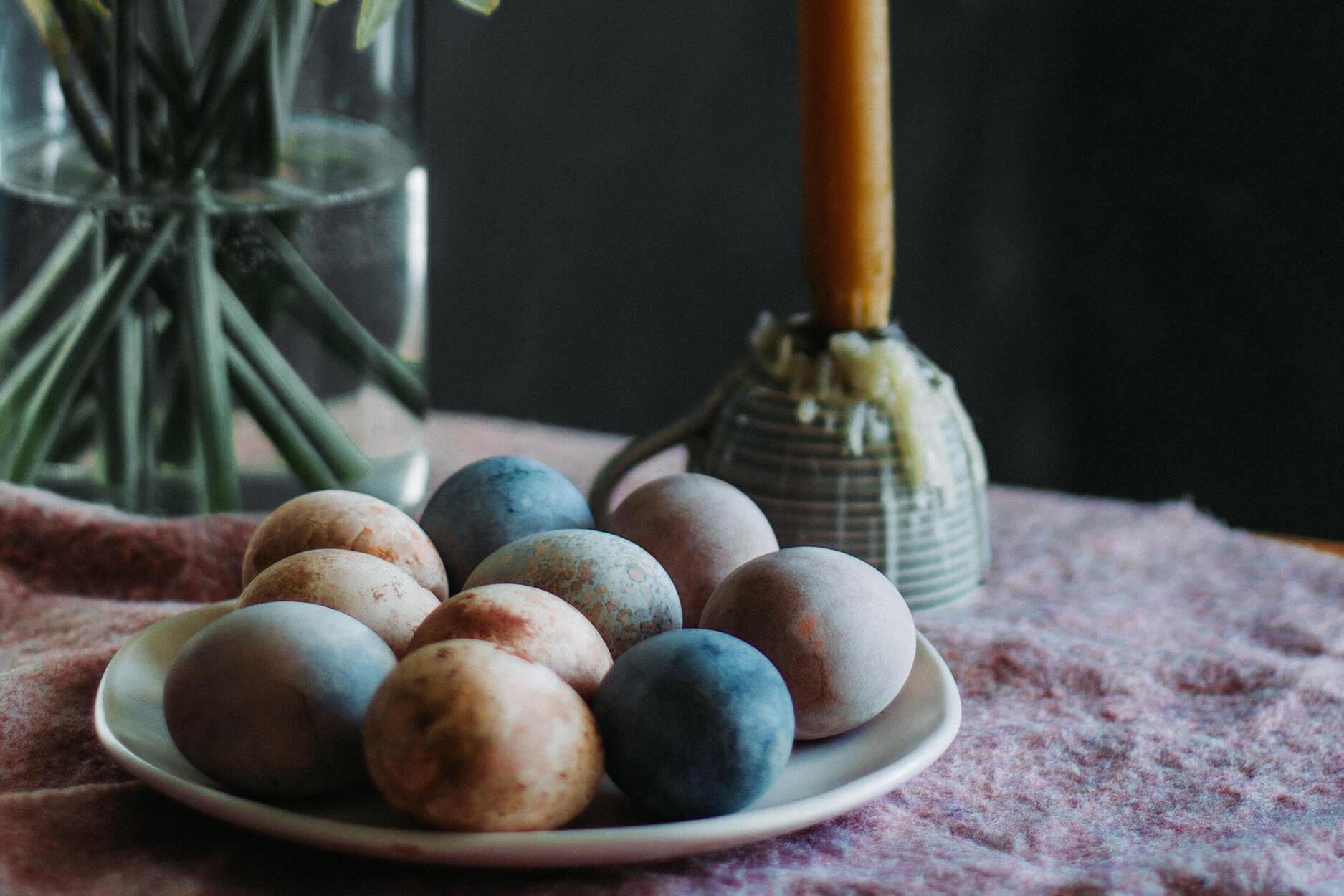 Easter eggs on a white plate on a pink linen table cloth