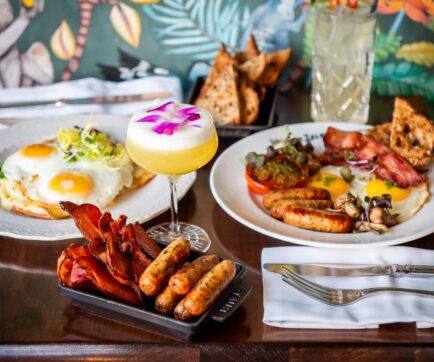 Eggs Hemingway, The Full Selby, and cocktails on a wood top table