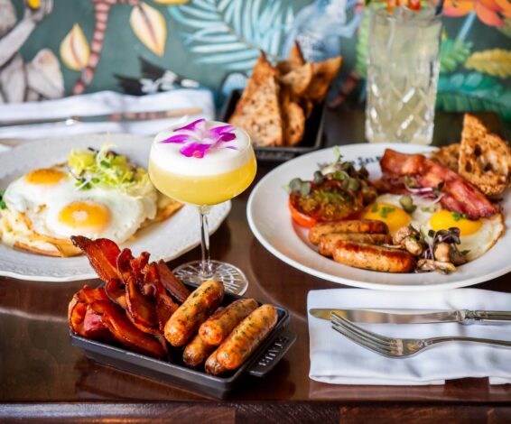 Eggs Hemingway, The Full Selby, and cocktails on a wood top table