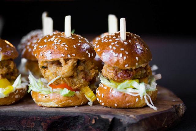 a wooden serving platter with crispy fried chicken sliders at The Carlu