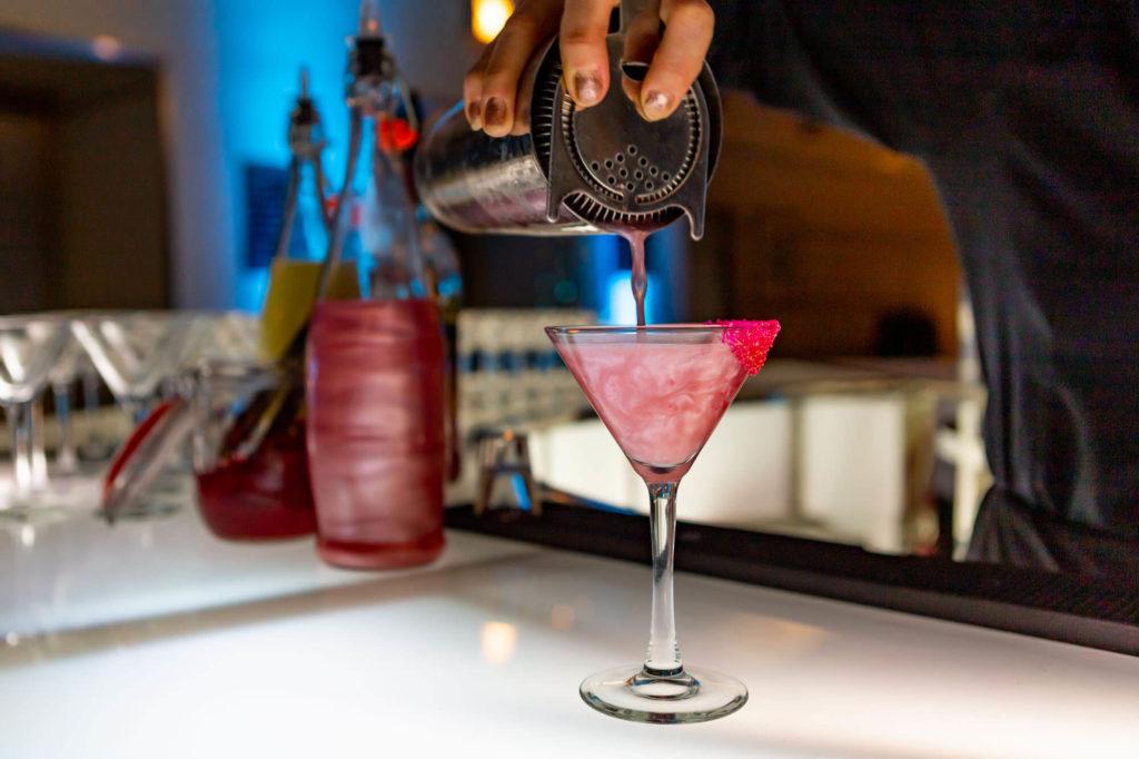 Shimmery cocktail being poured into a martini glass at The Carlu