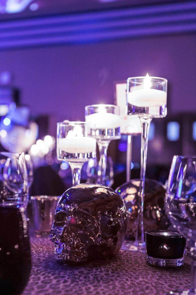 Candles and metallic skull table toppers at a gala event at The Carlu