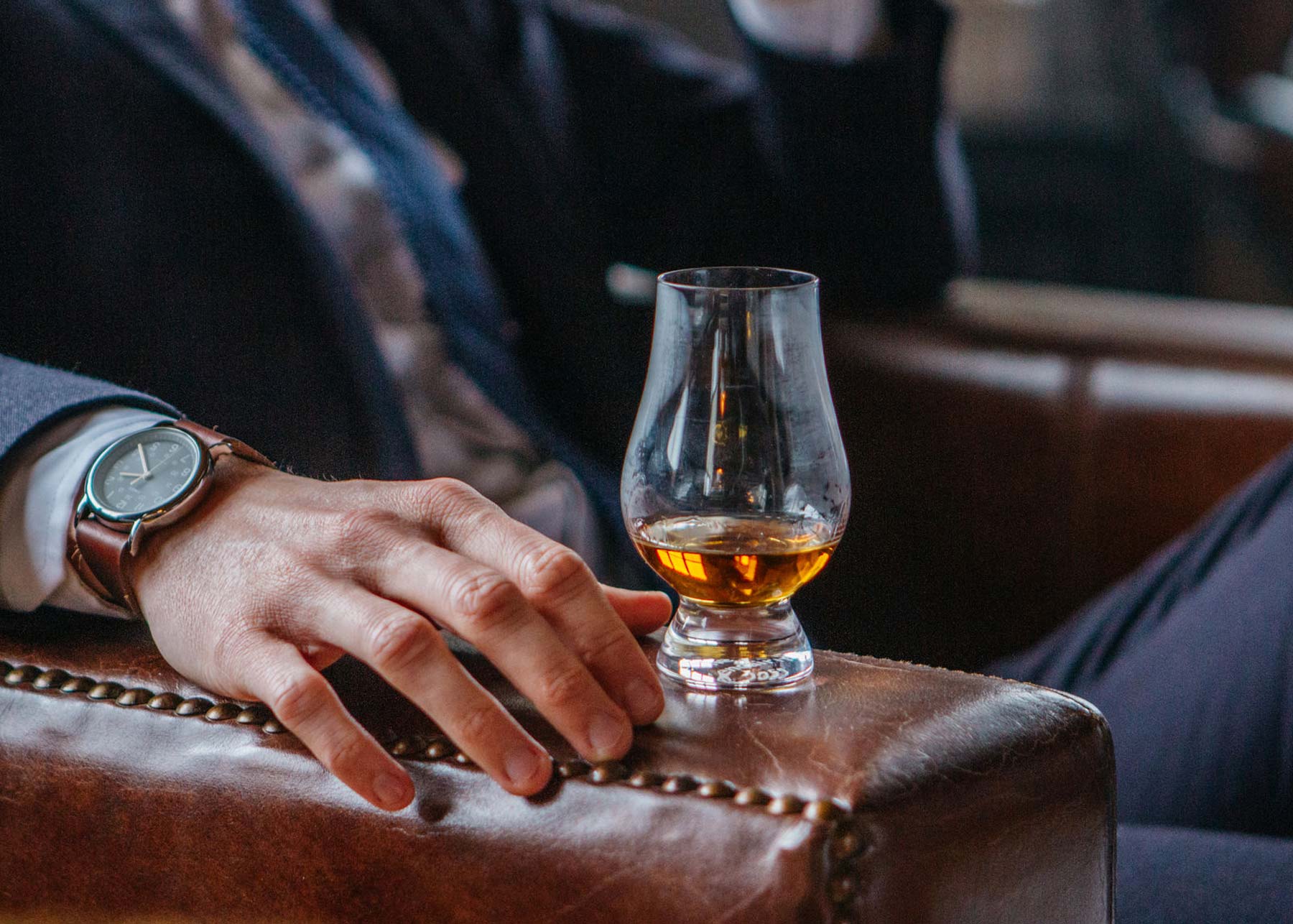man sitting with cocktail on armrest