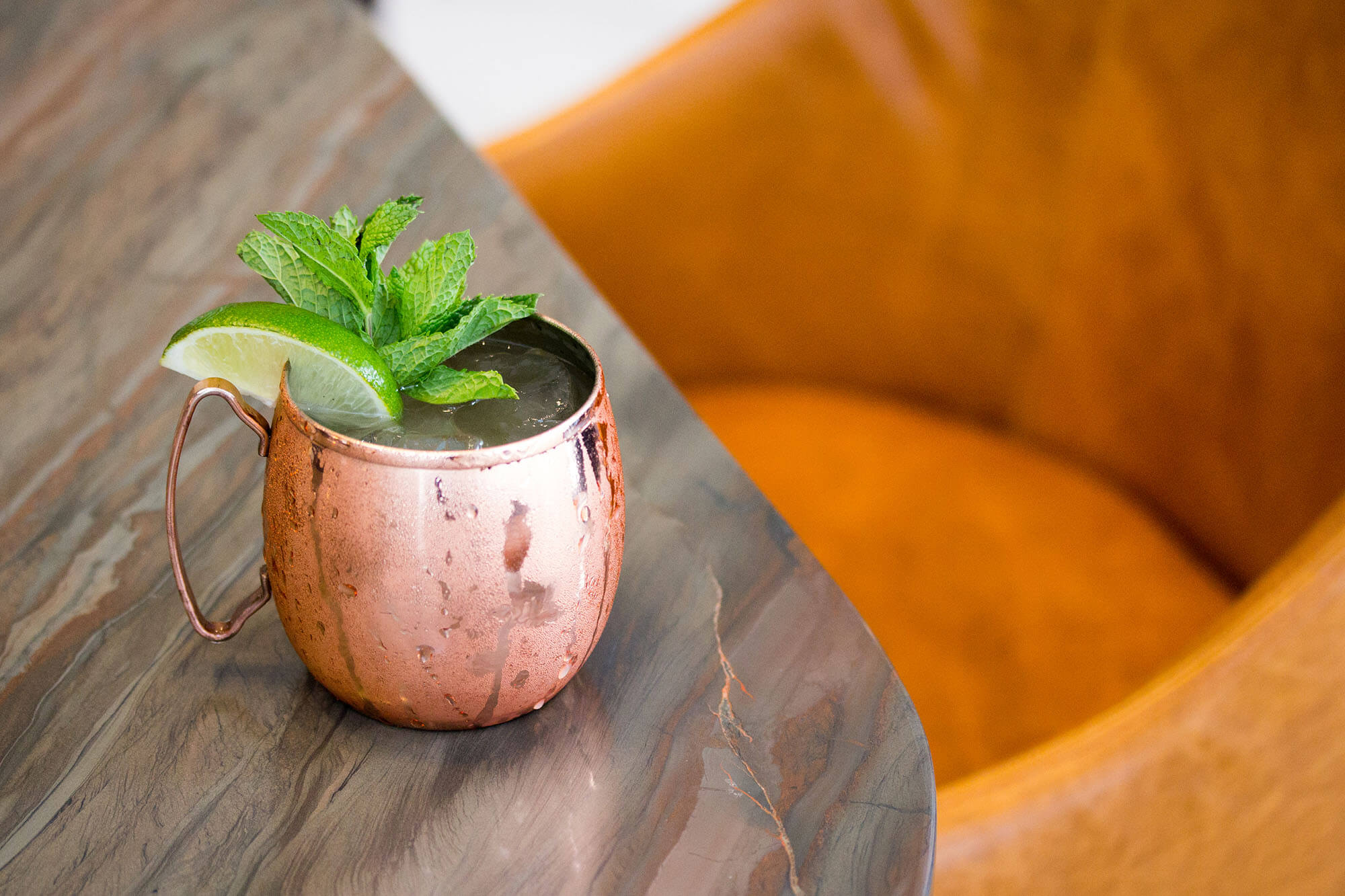 drink in copper cup garnished with lime and mint on marble surface