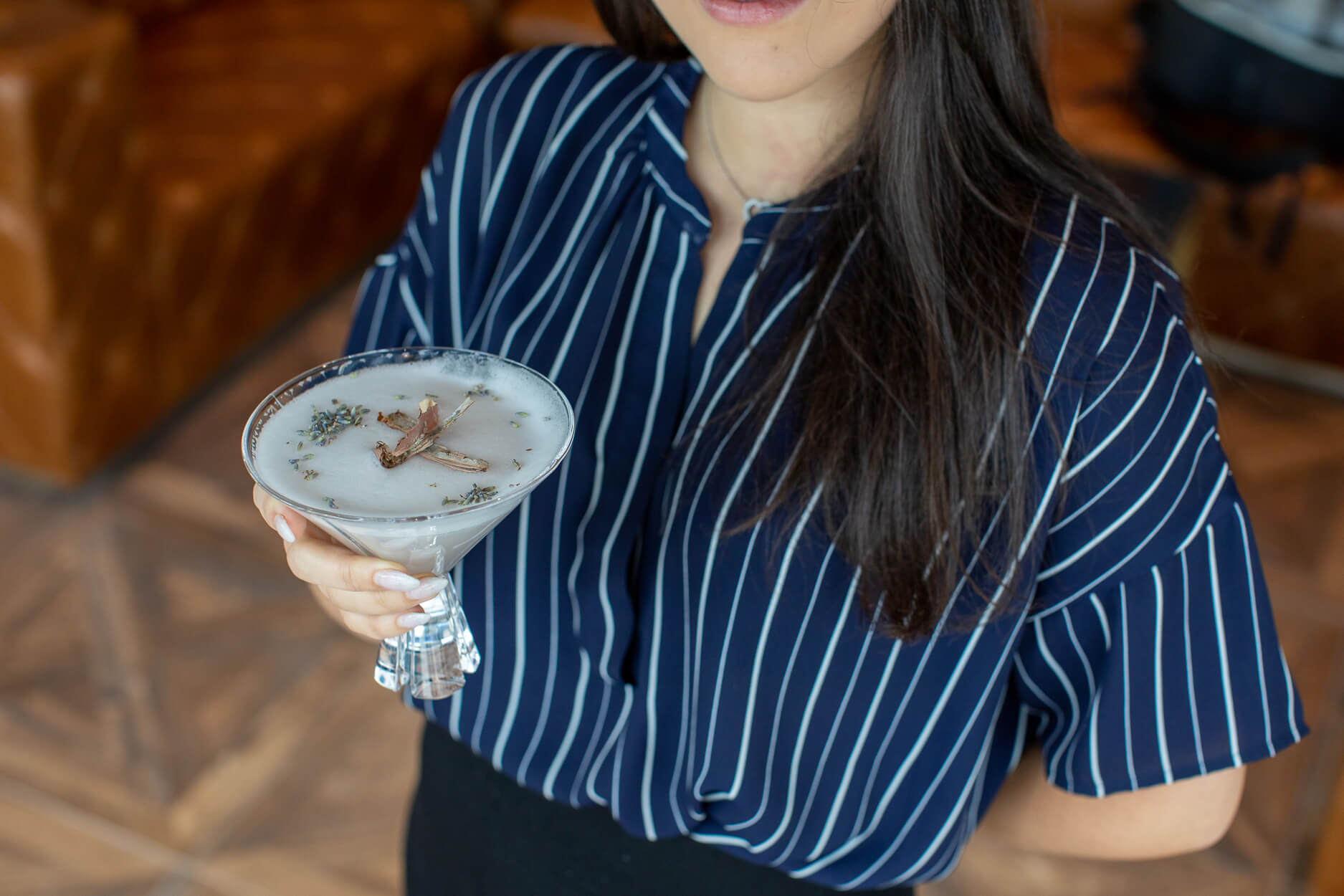 Woman with long dark hair holding a cocktail at Alchemy