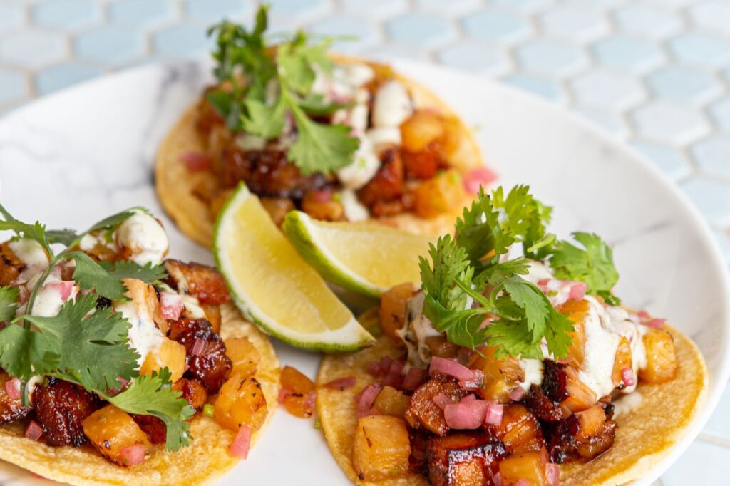 Three Roasted Squash Tacos on a plate with lime wedges