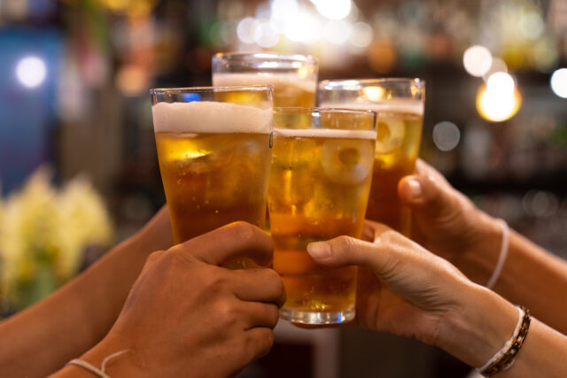 Group of happy friends drinking and toasting beer at brewery bar