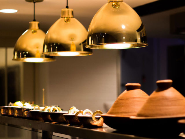 gold lights hanging over copper bowls and tagine cooking vessels