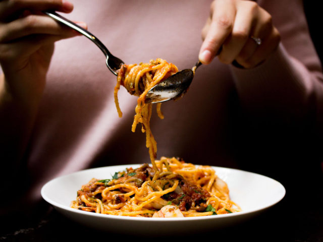 guest twirling spaghetti on a fork and spoon at Babel restaurant