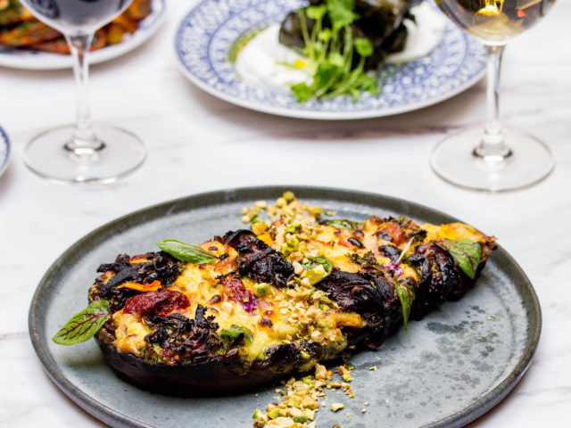 whole stuffed eggplant on a light grey plate