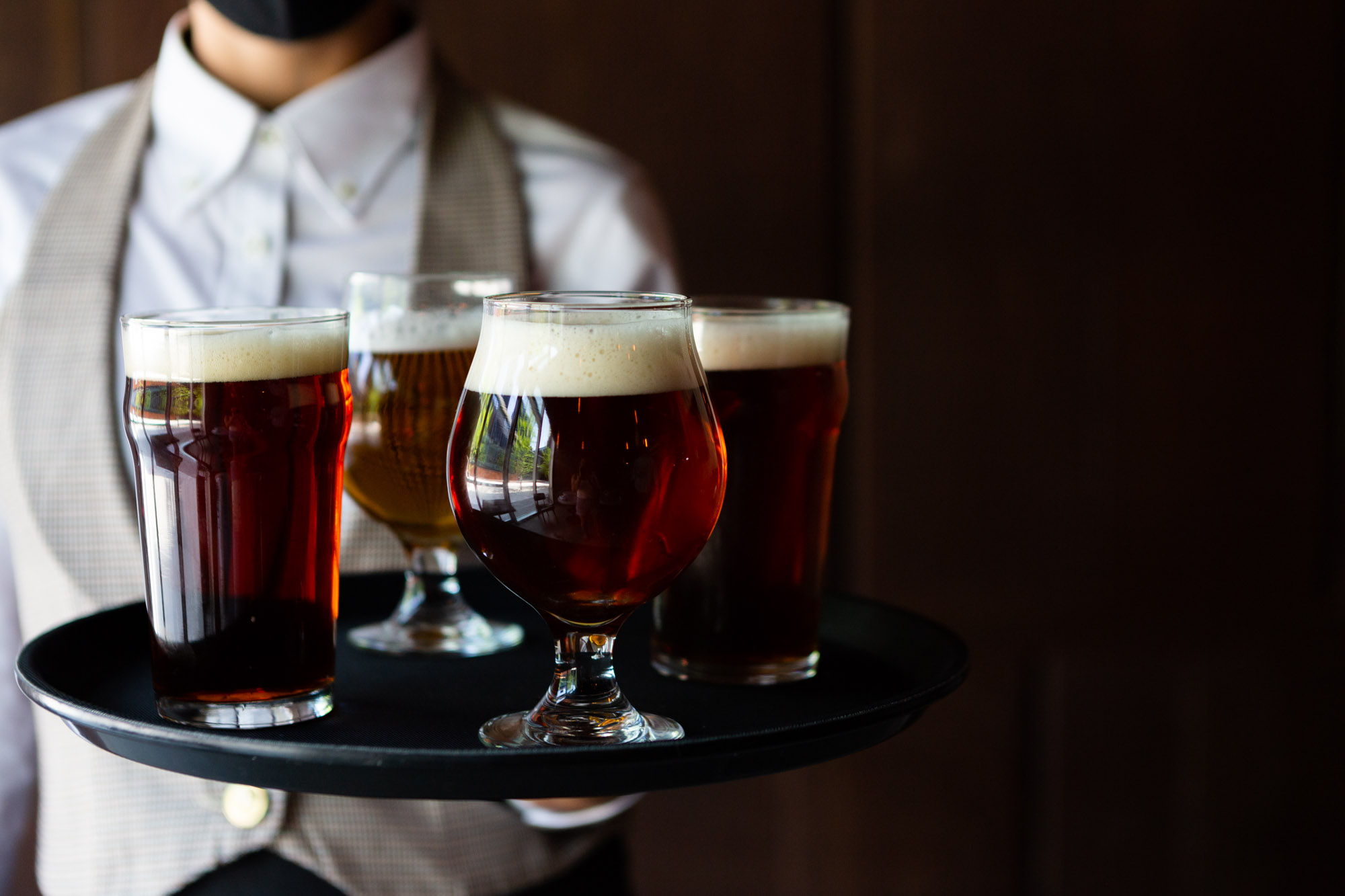 A server holding a tray of craft beers